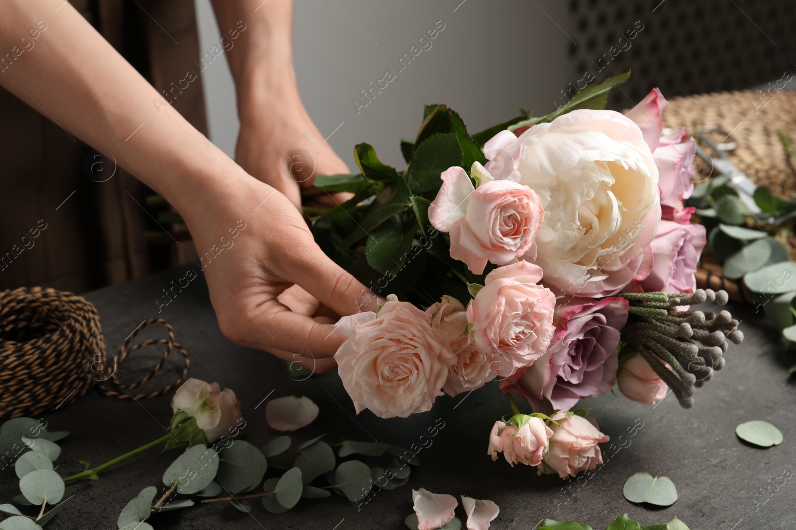 Photo of Florist creating beautiful bouquet at black table indoors, closeup