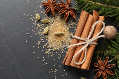 Photo of Different spices, nut and fir branches on gray table, flat lay. Space for text