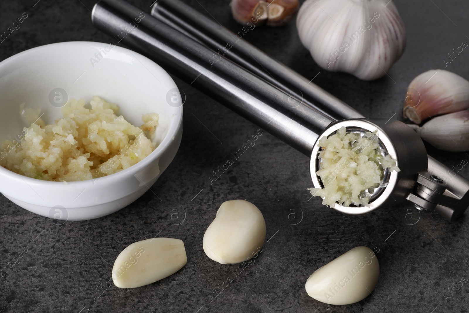 Photo of Garlic press, cloves and mince on grey table, closeup