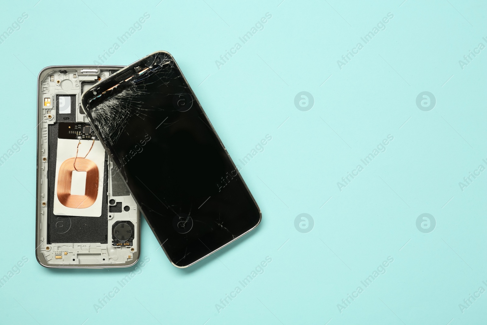 Photo of Damaged smartphone on light blue background, flat lay with space for text. Device repairing