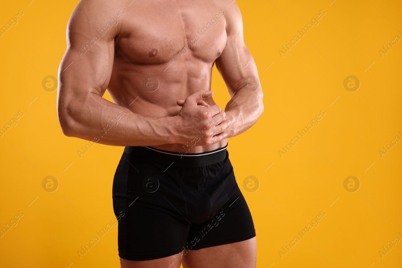 Photo of Young man is stylish black underwear on orange background, closeup