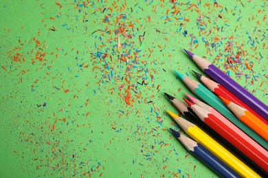 Photo of Color pencils and shavings on green background