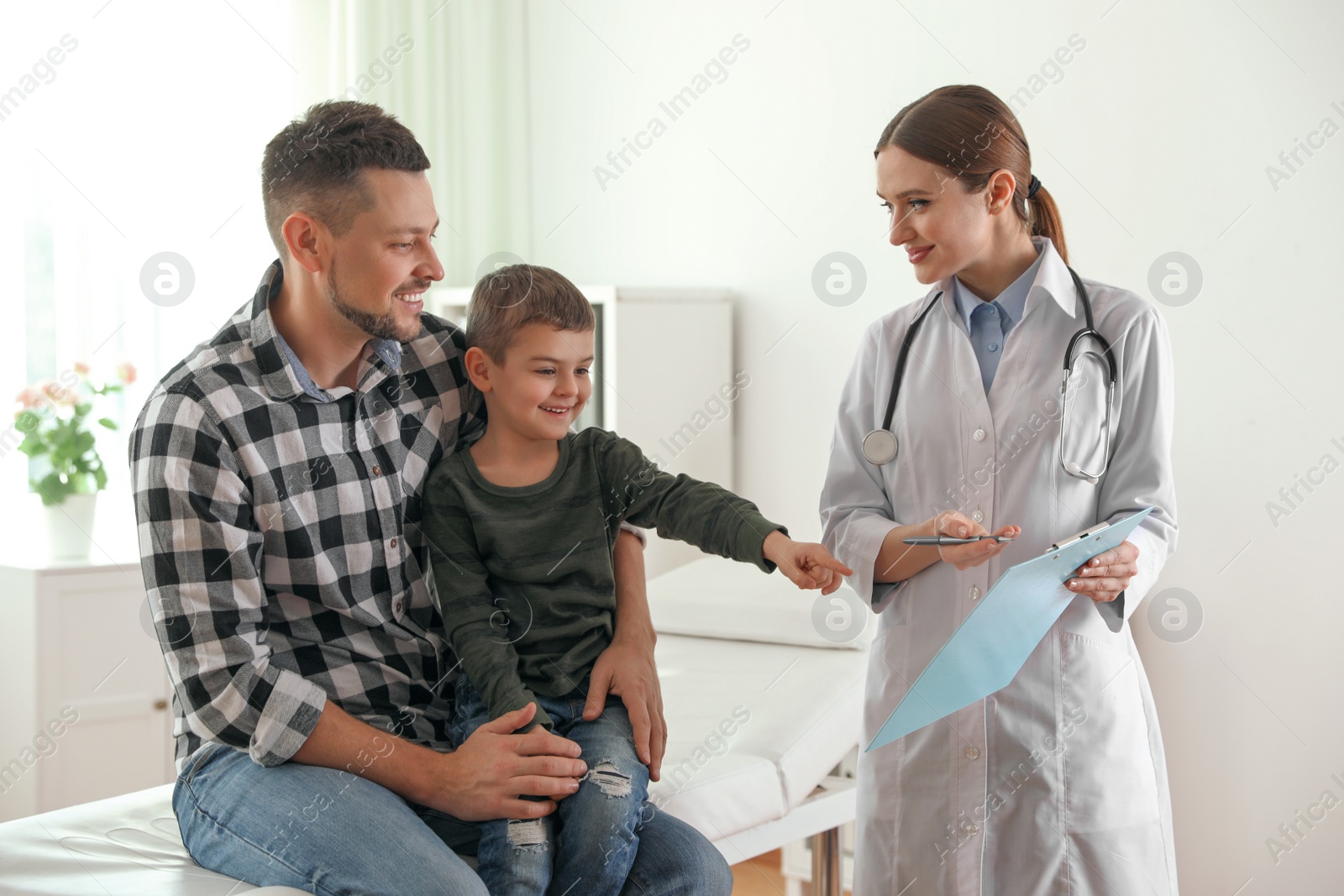 Photo of Father and son visiting pediatrician. Doctor working with patient in hospital