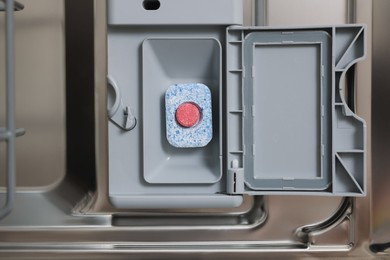 Photo of Open dishwasher door with detergent tablet, top view