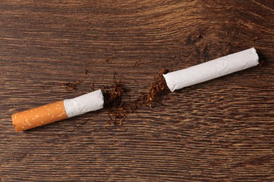 Broken cigarette and tobacco on wooden table, top view. No smoking concept