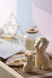 Photo of Beautiful body shaped candles and jewelry on tray indoors