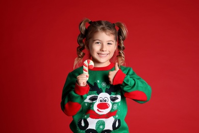 Photo of Cute little girl with Christmas gingerbread cookie on red background