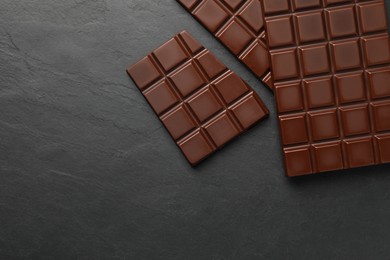 Pieces of tasty chocolate bars on grey table, flat lay. Space for text