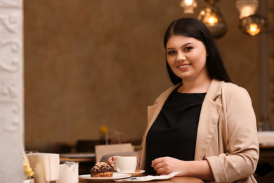 Beautiful overweight woman at table in cafe. Plus size model