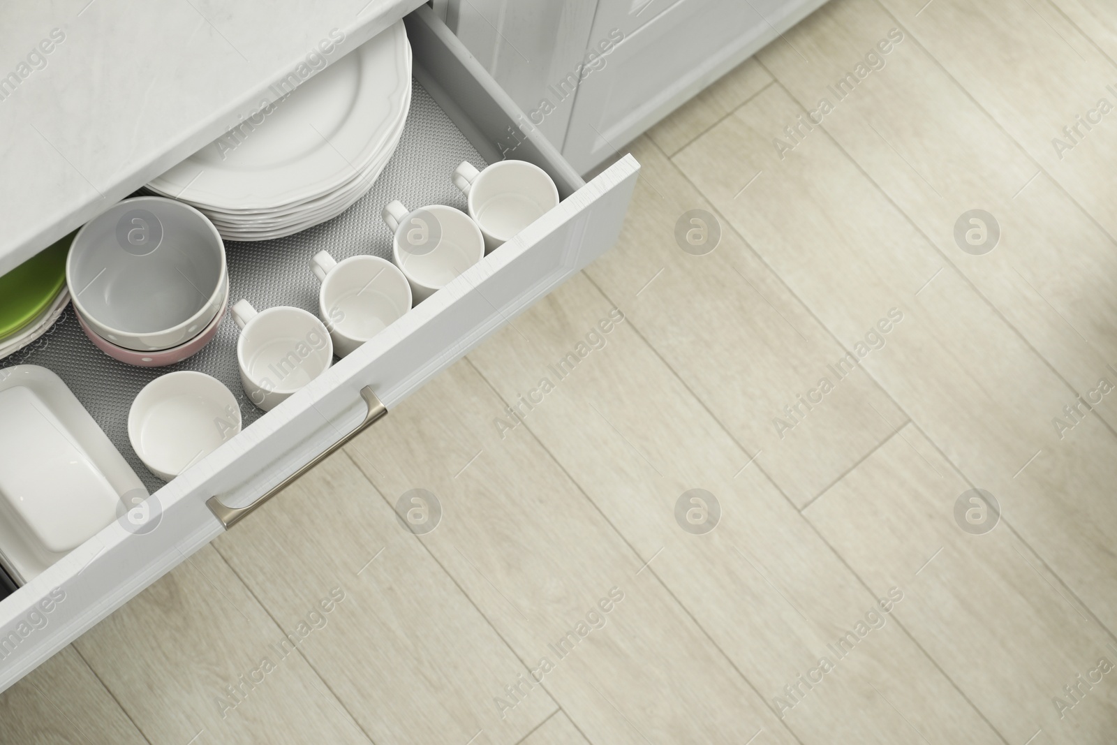 Photo of Clean plates, bowls, butter dish and cups in drawer indoors, top view. Space for text