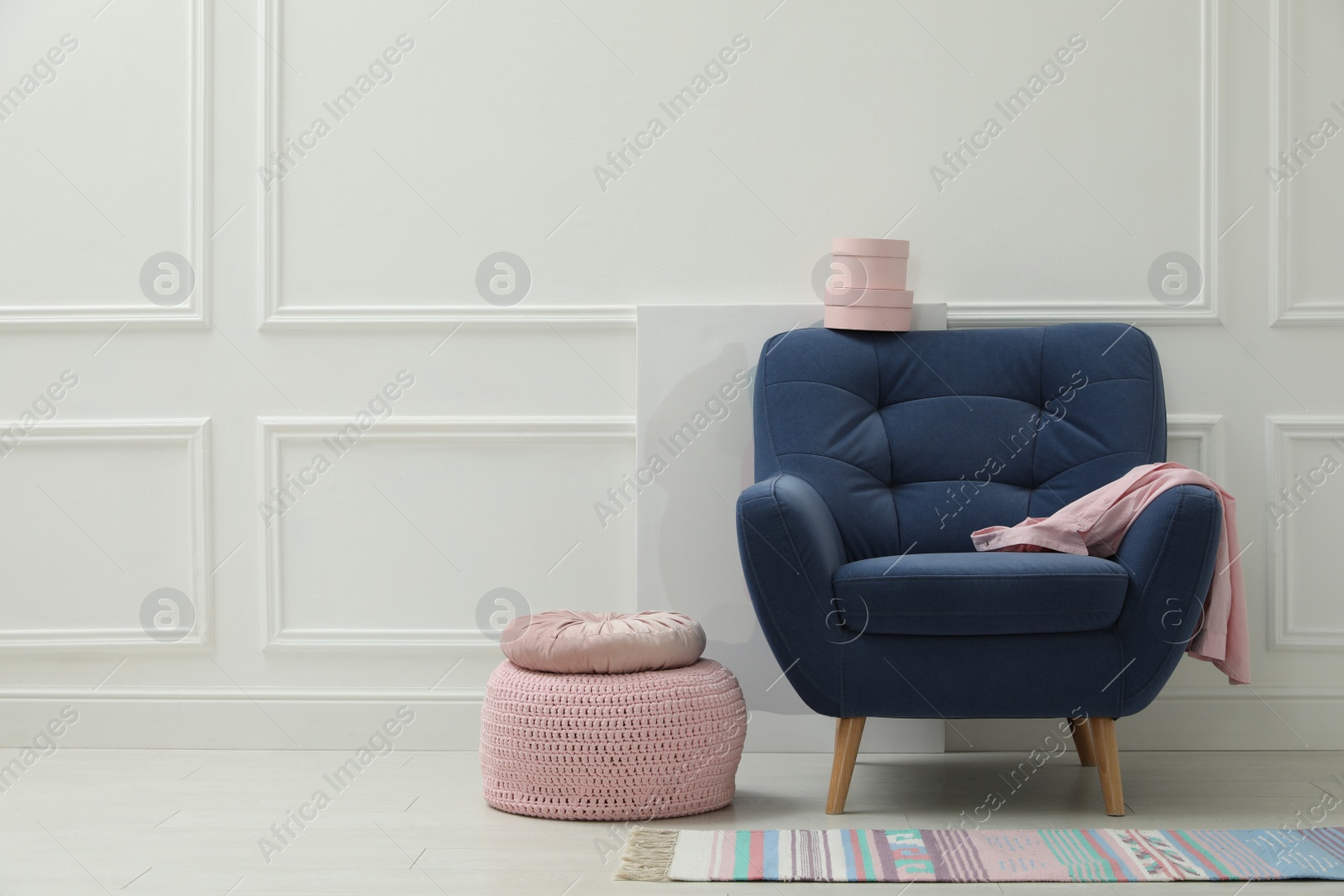 Photo of Stylish room interior with pouf, armchair and decor elements. Space for text