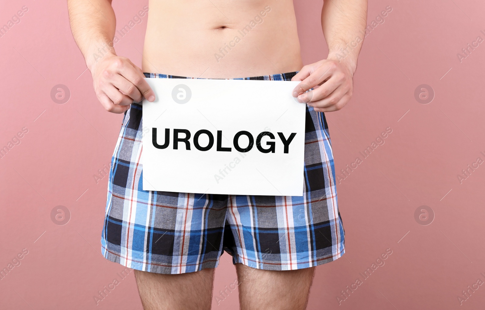 Photo of Young man holding paper with word UROLOGY on color background