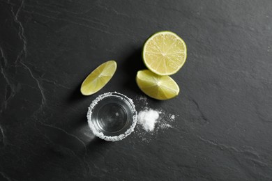 Photo of Mexican Tequila shot, lime slices and salt on black table, flat lay