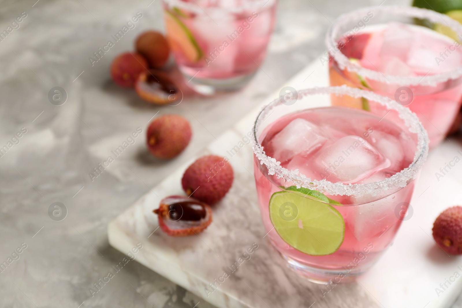 Photo of Lychee cocktail with lime and ice on grey table, space for text