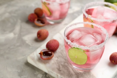 Lychee cocktail with lime and ice on grey table, space for text