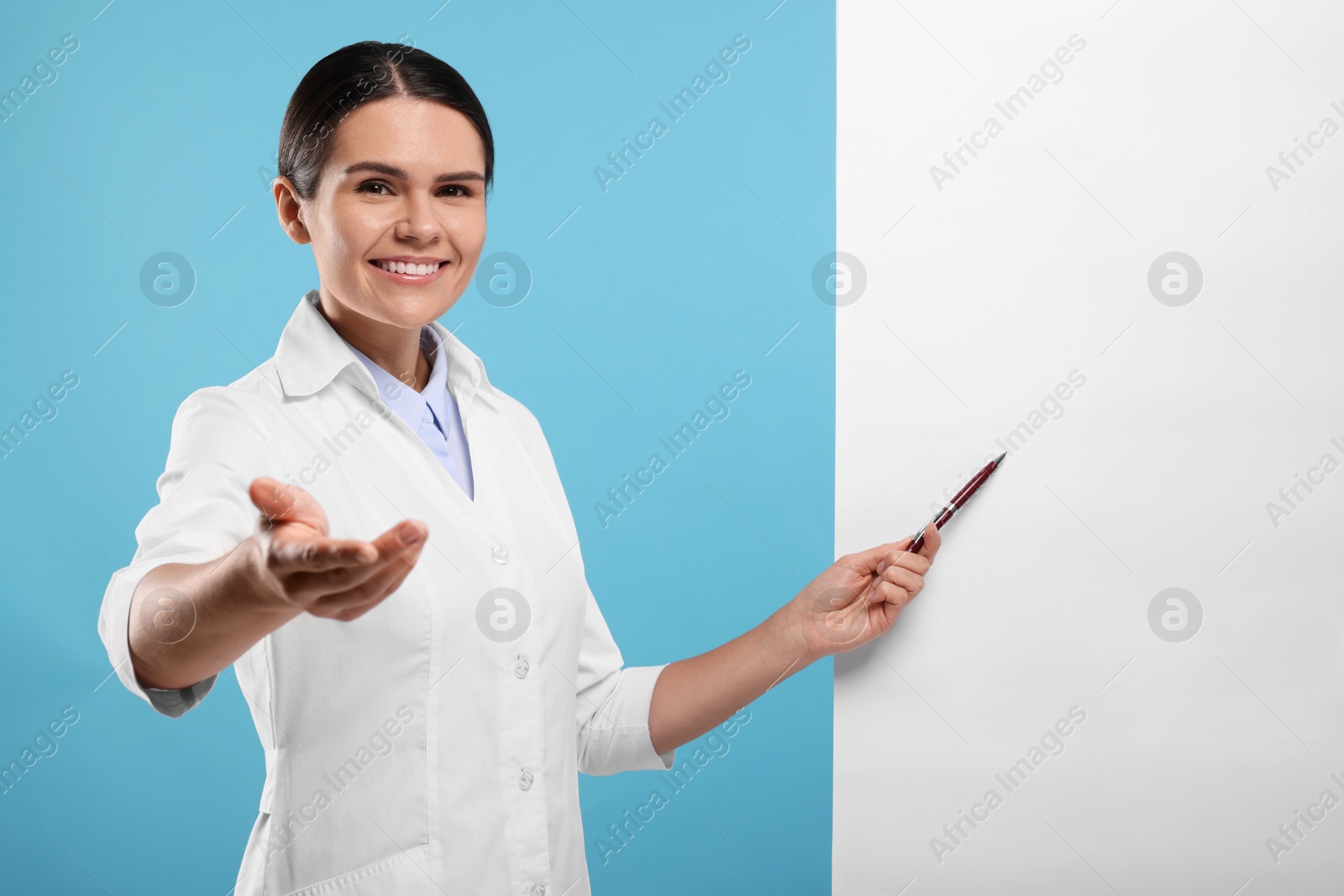 Photo of Ophthalmologist pointing at blank banner on light blue background, space for text