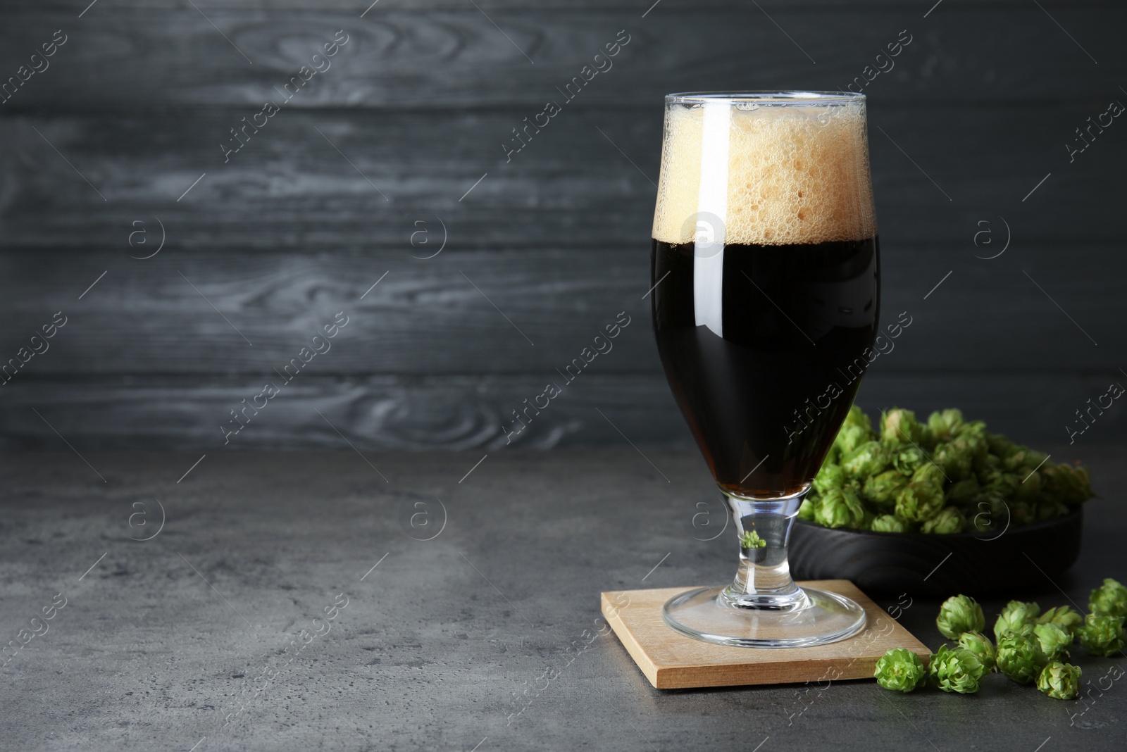 Photo of Composition with tasty beer and fresh green hops on grey table. Space for text