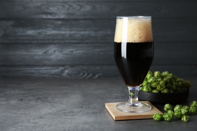 Photo of Composition with tasty beer and fresh green hops on grey table. Space for text