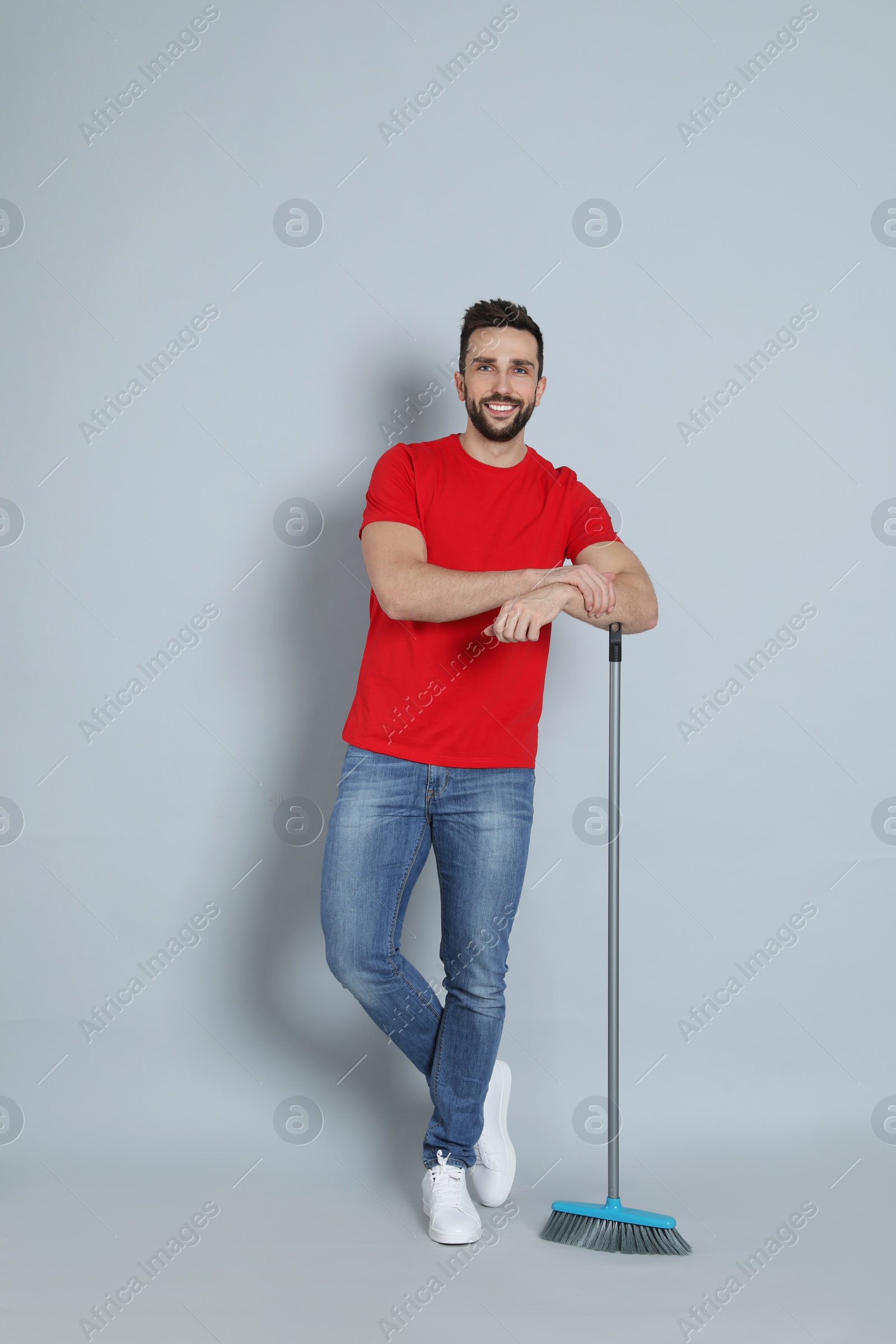 Photo of Handsome man with broom on grey background