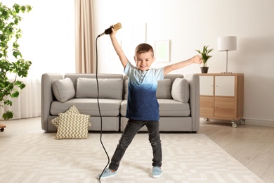 Photo of Cute funny boy with microphone in living room