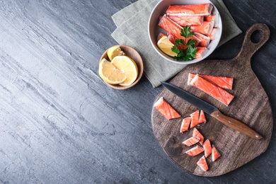 Photo of Flat lay composition with crab sticks, knife and lemon on grey background, space for text