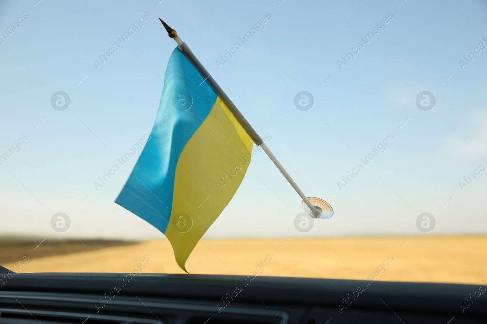 Photo of National flag of Ukraine on windshield inside car, closeup