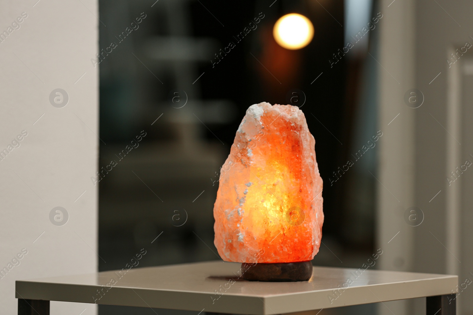 Photo of Himalayan salt lamp on table in room. Space for text