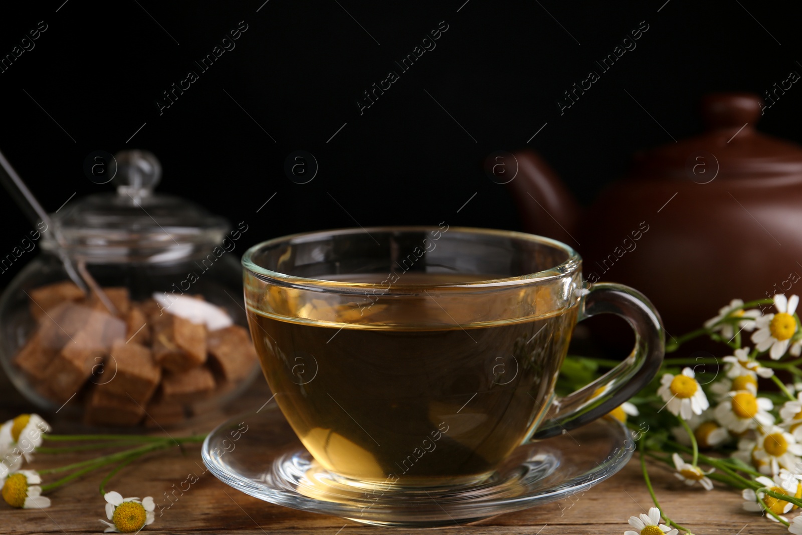 Photo of Delicious chamomile tea in glass cup on wooden table