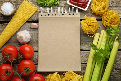 Photo of Blank recipe book surrounded by different ingredients on wooden table, flat lay. Space for text