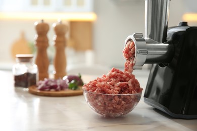 Photo of Modern meat grinder and products on white marble table in kitchen. Space for text