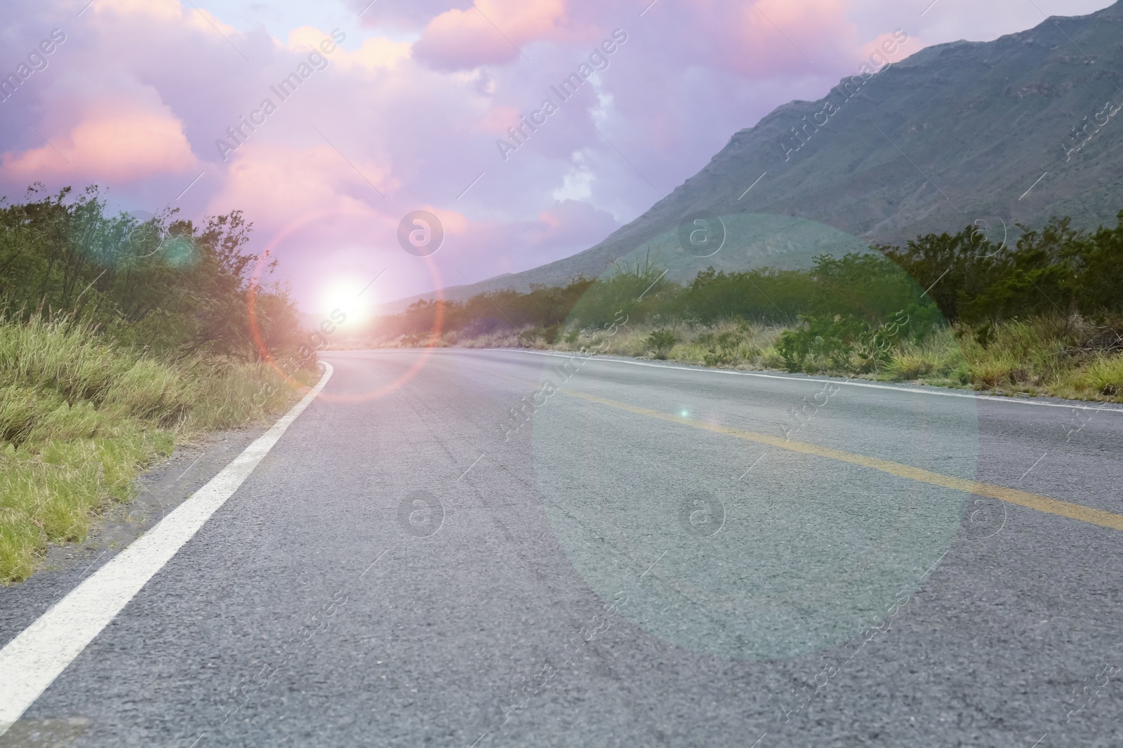 Image of Empty asphalt road, bushes and mountain at beautiful sunset