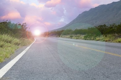 Image of Empty asphalt road, bushes and mountain at beautiful sunset