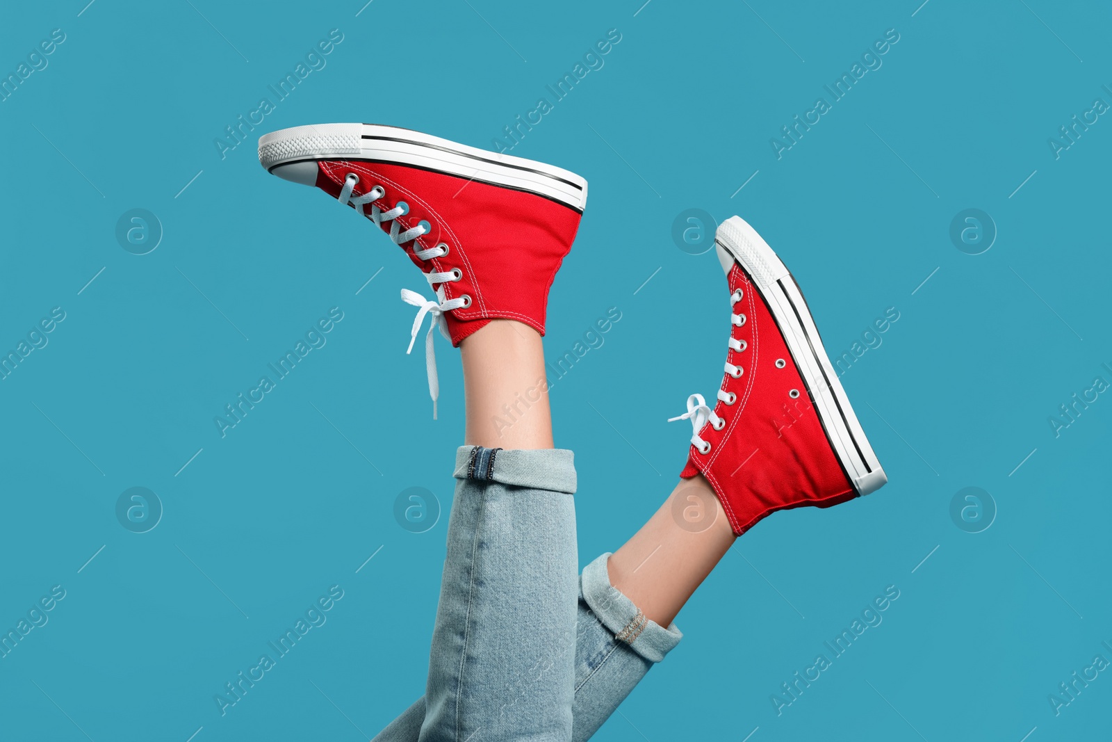 Photo of Woman in stylish gumshoes on light blue background, closeup