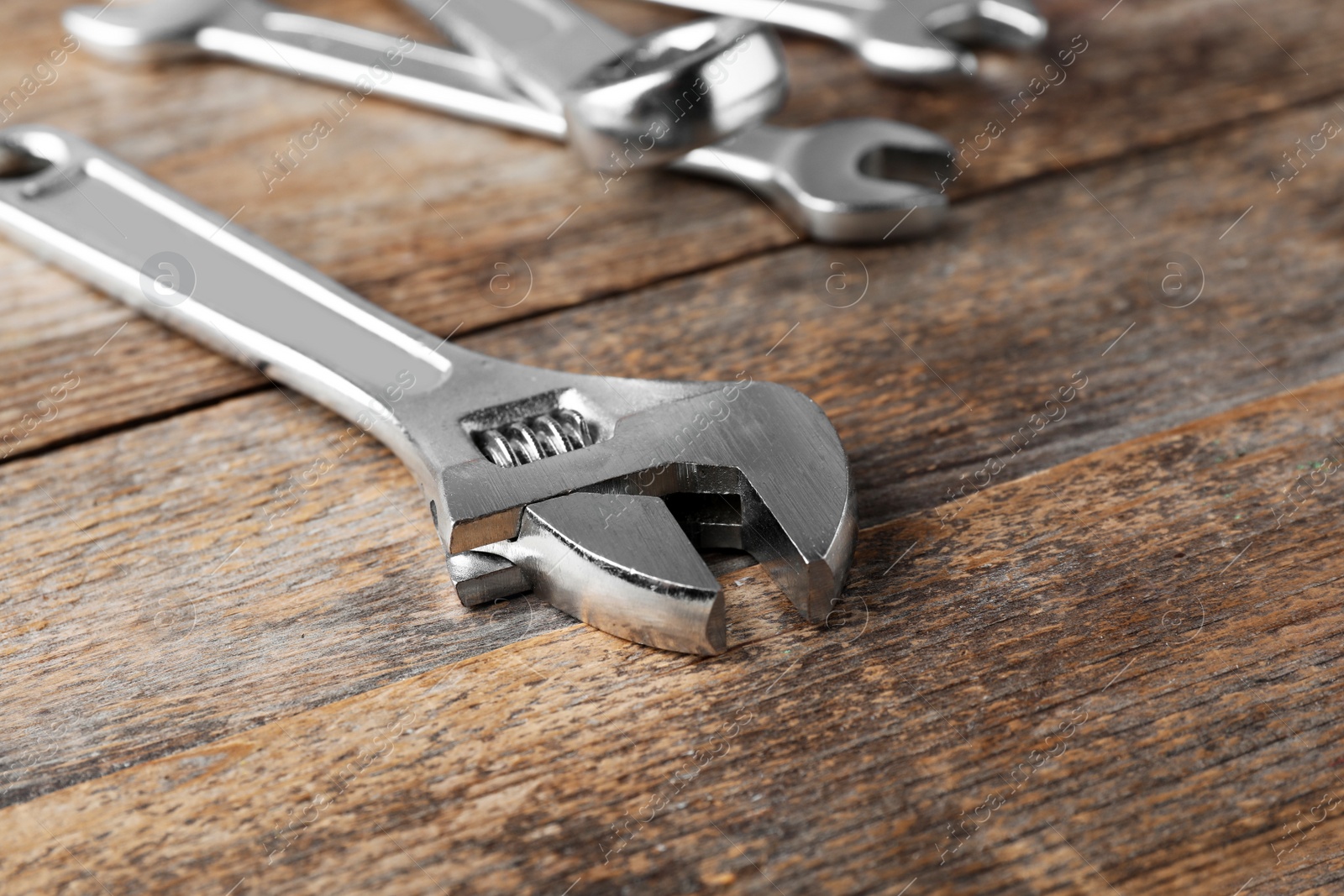 Photo of Adjustable wrench on wooden background, closeup with space for text. Plumber tools