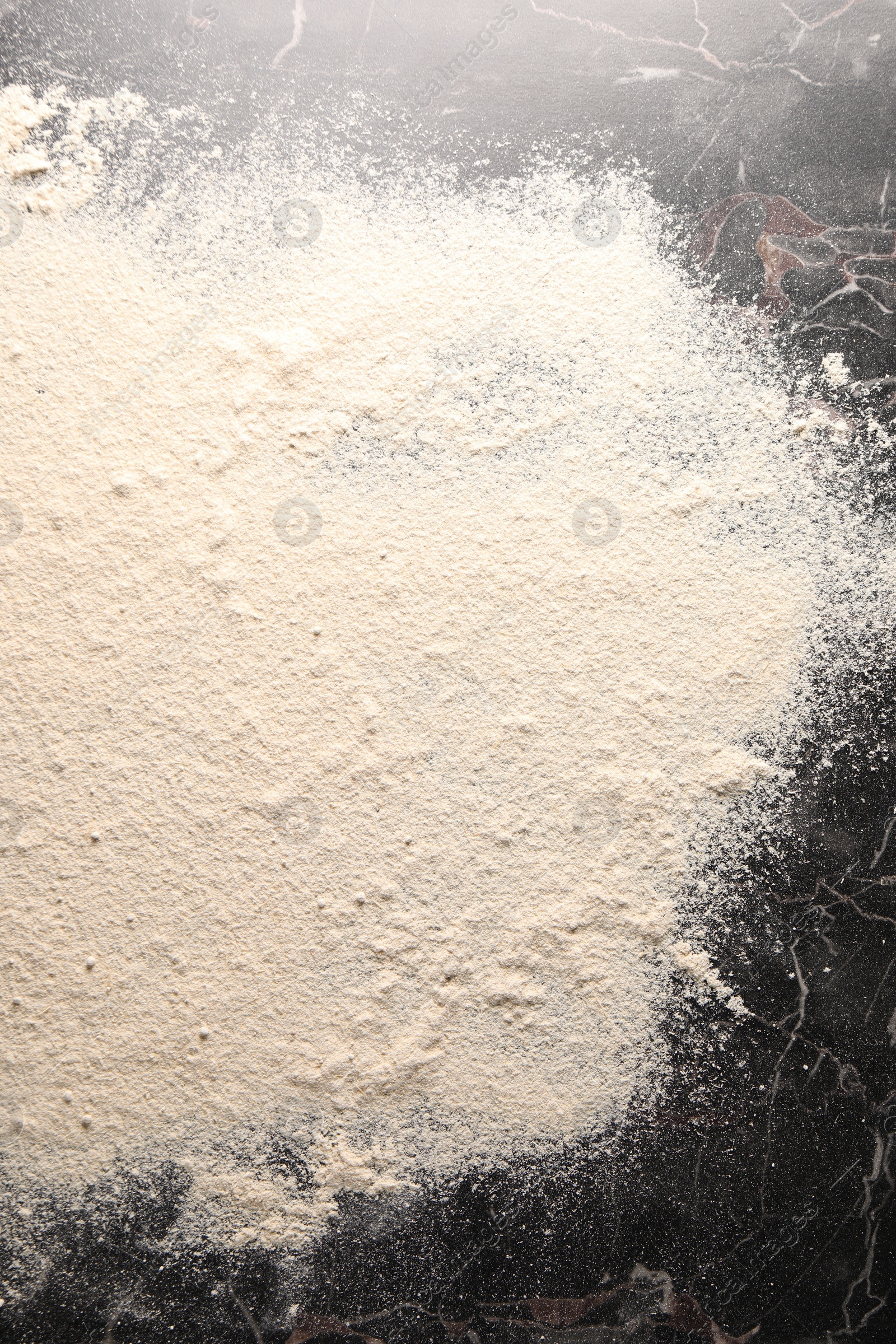 Photo of Pile of flour on black marble table, top view