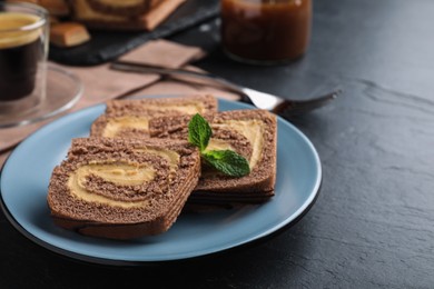 Photo of Tasty chocolate cake roll with cream on black table