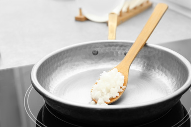 Frying pan with coconut oil on induction stove, closeup. Healthy cooking