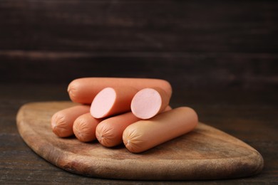 Photo of Whole and cut delicious boiled sausages on wooden table