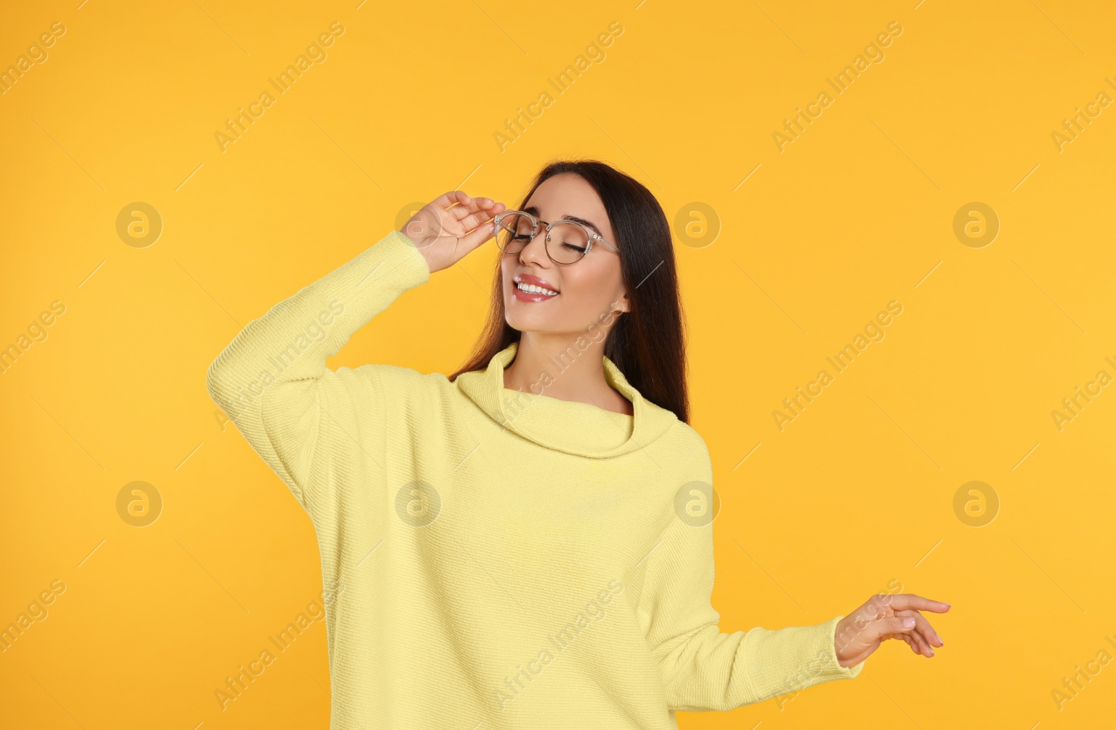 Photo of Beautiful young woman wearing warm sweater on yellow background