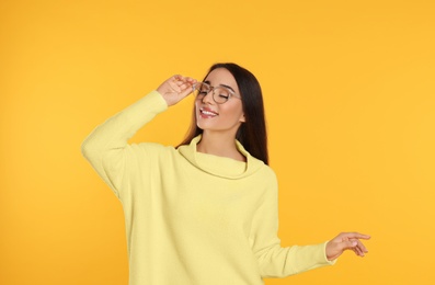 Beautiful young woman wearing warm sweater on yellow background