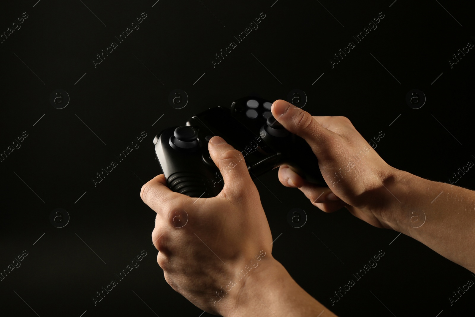 Photo of Man holding video game controller on black background, closeup