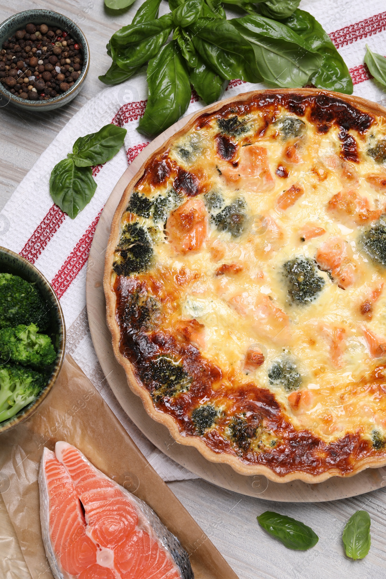 Photo of Delicious homemade quiche and ingredients on wooden table, flat lay