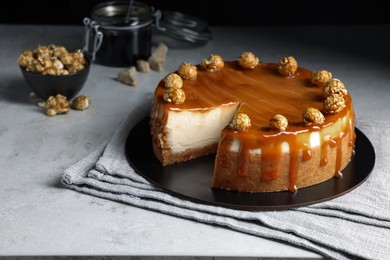 Sliced delicious cheesecake with caramel and popcorn on light grey table