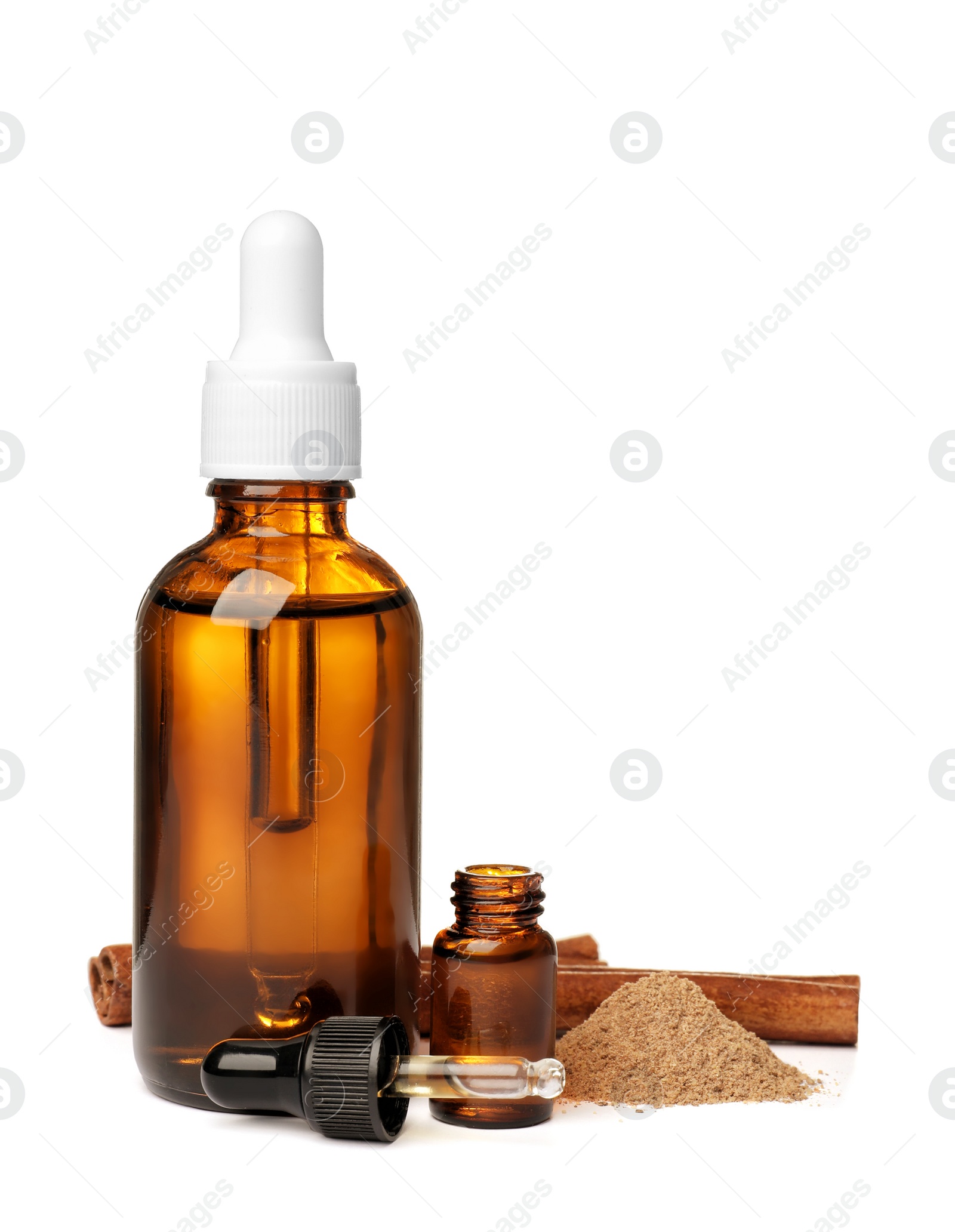 Photo of Bottles of cinnamon oil, dropper, powder and stick on white background