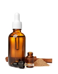 Photo of Bottles of cinnamon oil, dropper, powder and stick on white background