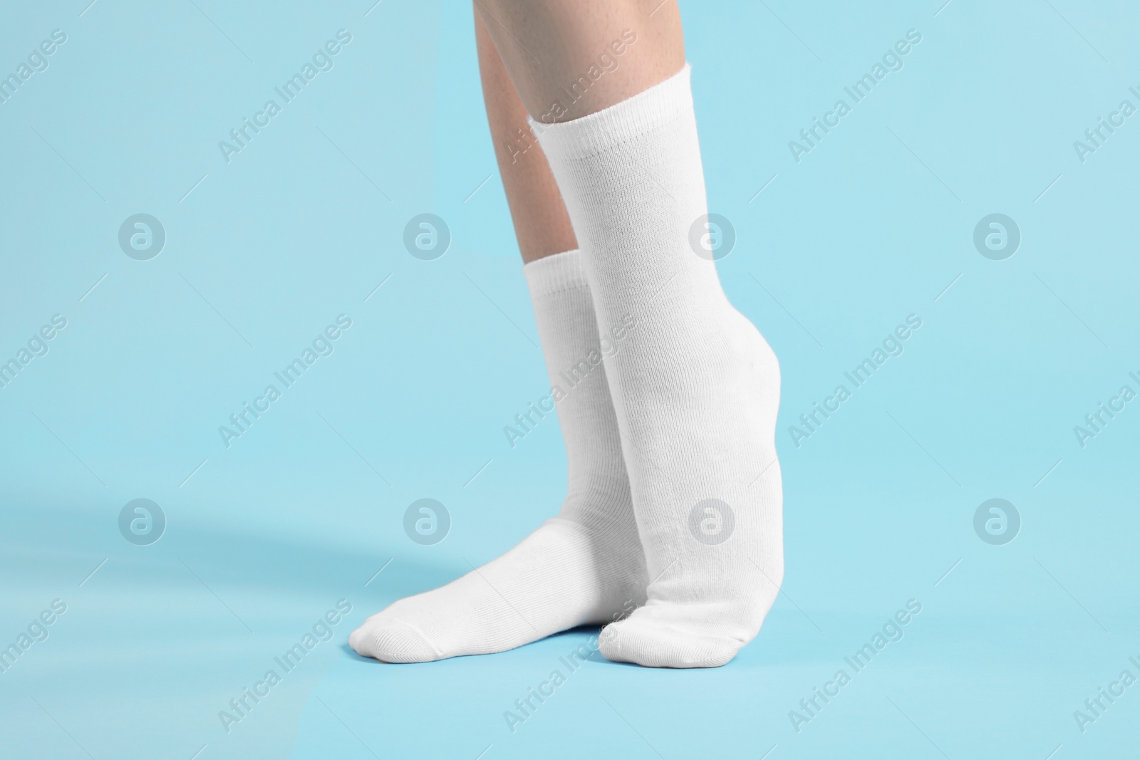 Photo of Woman in stylish white socks on light blue background, closeup