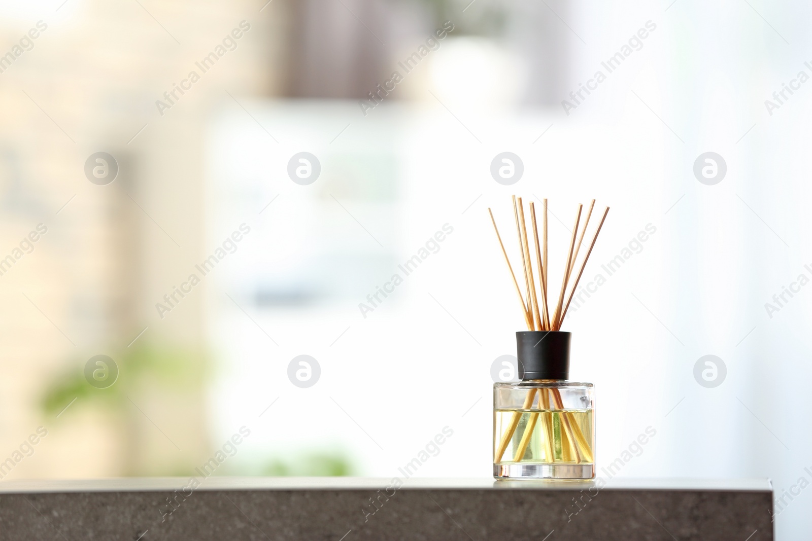 Photo of Aromatic reed air freshener on table against blurred background