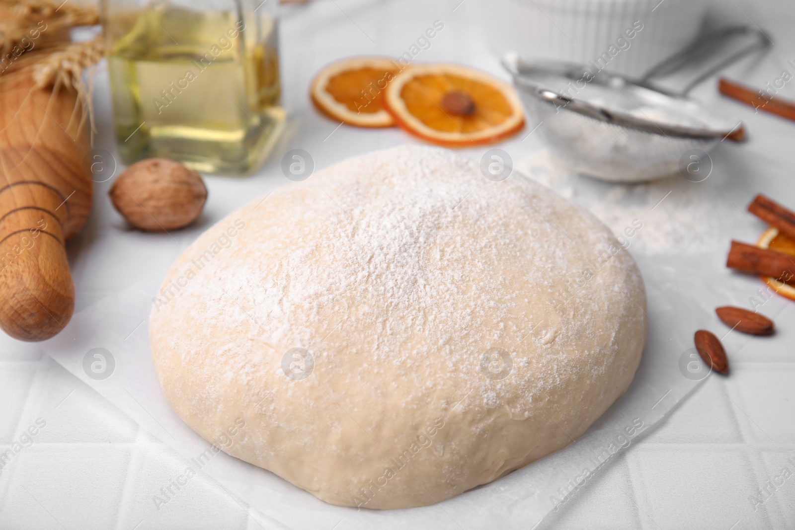 Photo of Fresh dough and ingredients on white tiled table, closeup