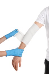 Doctor applying medical bandage onto patient's arm on white background, closeup