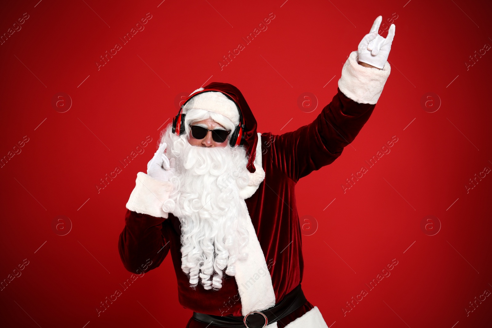 Photo of Santa Claus with headphones listening to Christmas music on red background